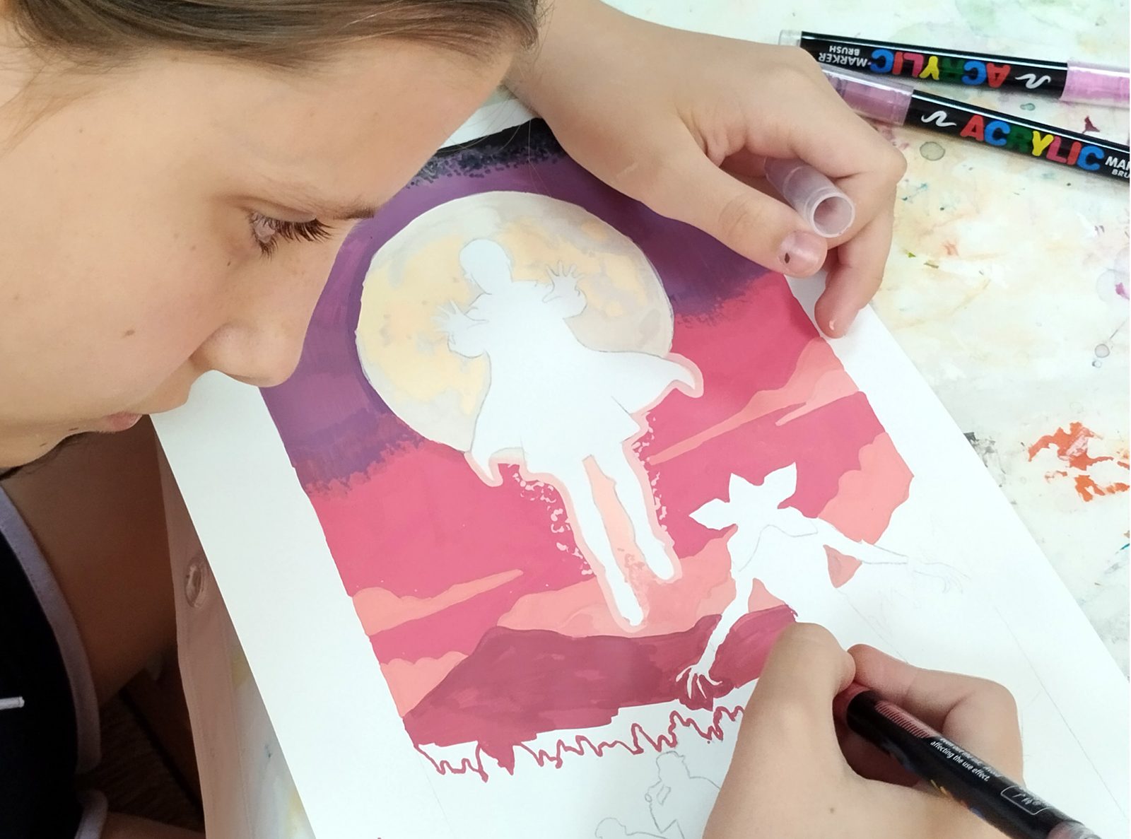 Alumna pintando una ilustración de la luna con rotuladores acrílicos en una clase de arte para jóvenes en Sevilla Este