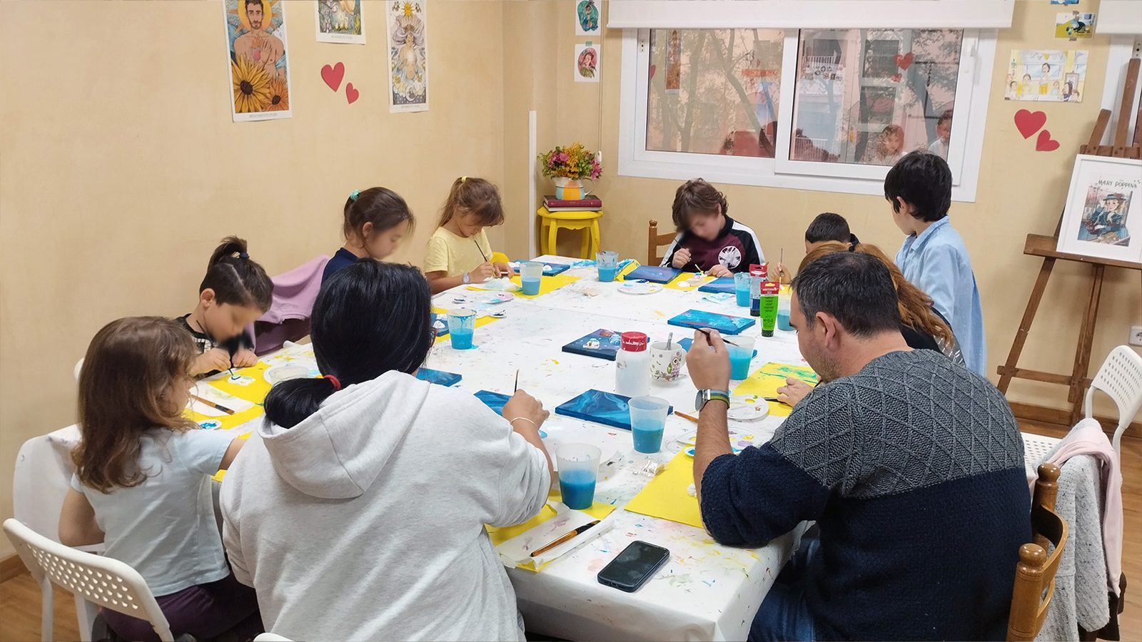 Grupo de peques y adultos pintando cuadros con acrílico en un taller artístico del estudio de Ana Toribio, Sevilla Este